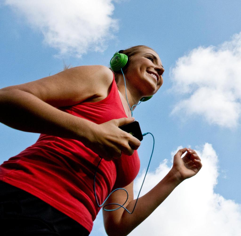 A woman jogs in the open air while listening to music.
